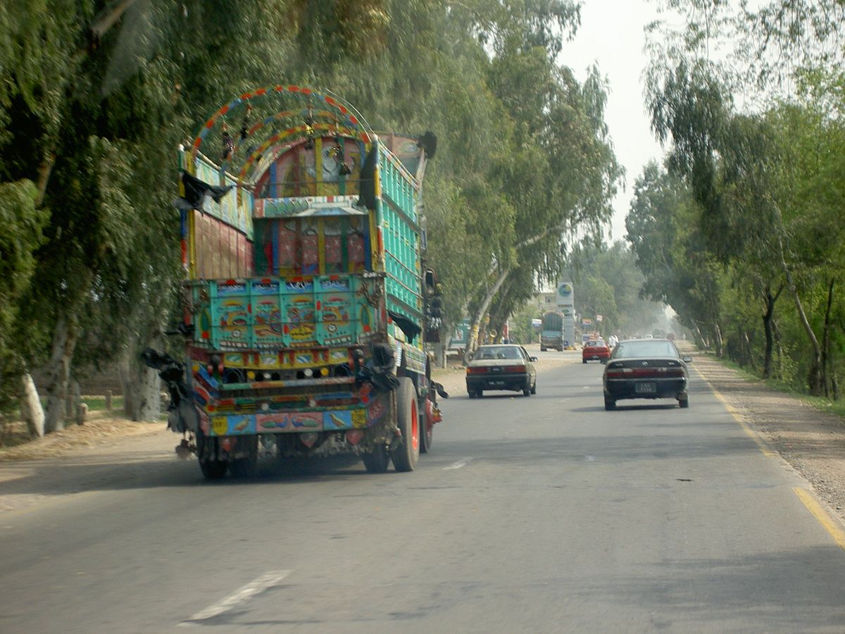 Tree-lined GT Road in Punjab with a colourfully decorated Pakistani truck and cars