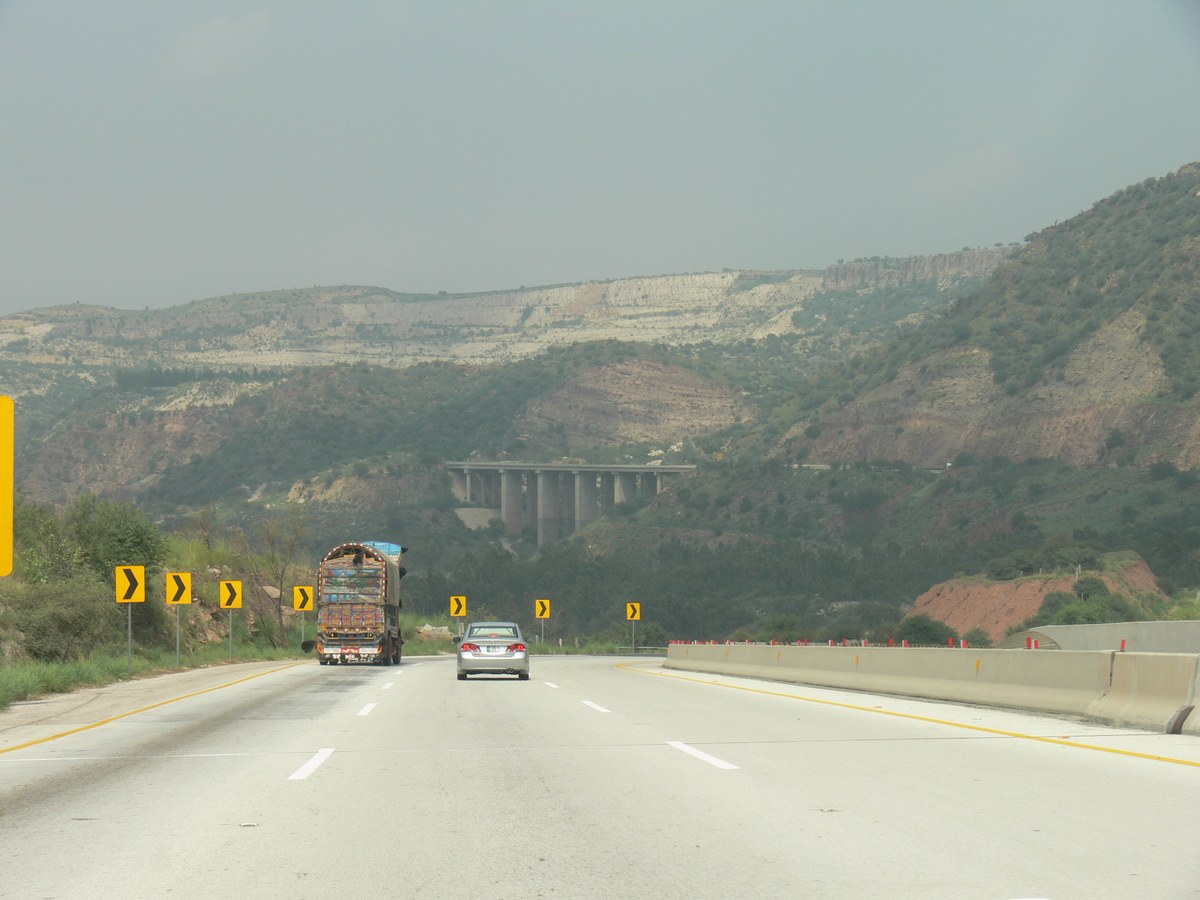 The M-2 motorway in the Salt Range with a high motorway bridge in the distance and traffic ahead
