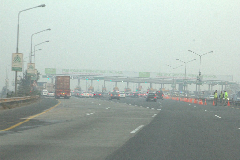 An M-2 motorway toll plaza in heavy winter haze with traffic cones and staff