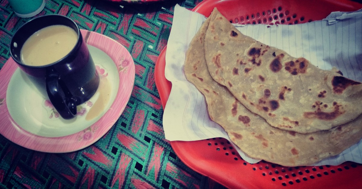 Paratha in a basket next to a cup of chai, a classic Pakistani breakfast