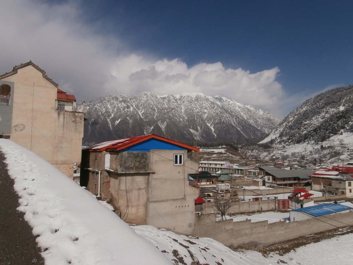 Kalam town buildings under snow with a mountain behind